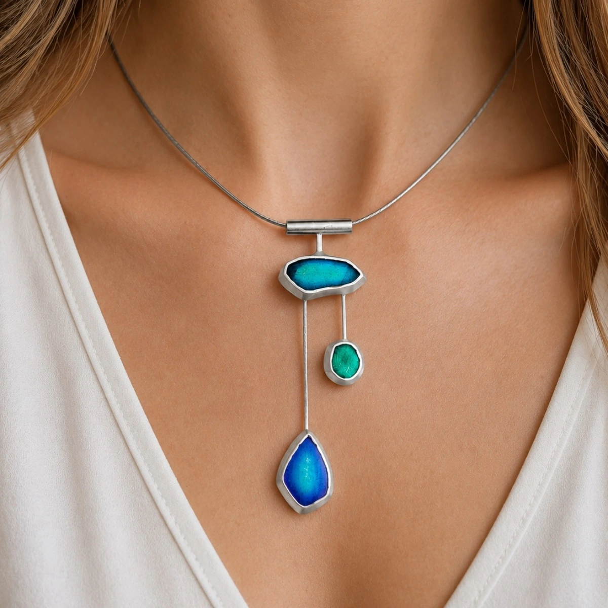 halsreif-silber-925-meerglas-tanz-der-wellen-dekollete Dreistufiger asymmetrischer Anhänger der Halskette Silber 925 Meerglas Tanz der Wellen mit blau-grüner Emaille an einem grauen Edelstahlreif; Collier mit Meerglas in Blau Grün