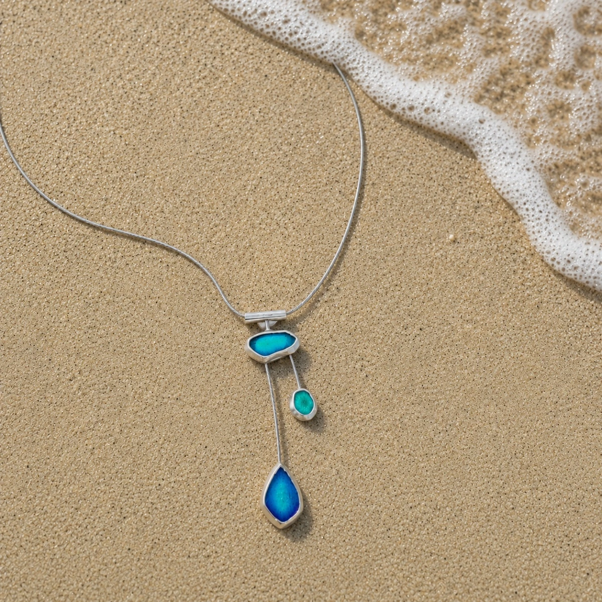 halsreif-silber-925-meerglas-tanz-der-wellen Dreistufiger asymmetrischer Anhänger der Halskette Silber 925 Meerglas Tanz der Wellen mit blau-grüner Emaille an einem grauen Edelstahlreif; Collier mit Meerglas in Blau Grün