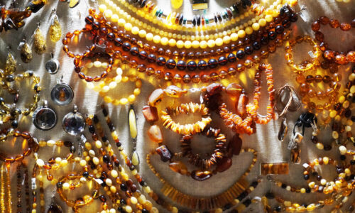 Bernsteinschmuck – Halsketten, Armbänder und Anhänger in verschiedenen Farbnuancen auf hellem Hintergrund